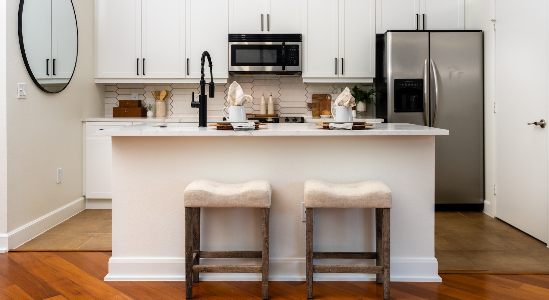kitchen with white cabinets island with barstools and stainless steel appliances
